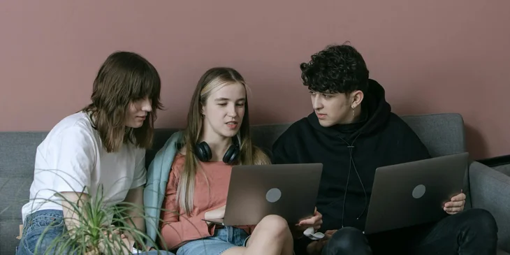 A group of young Gen Z people watching at a laptop.