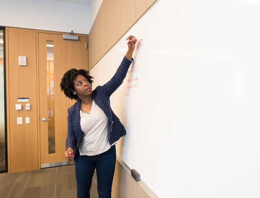 Assistant Professor teaches students while writing on the board