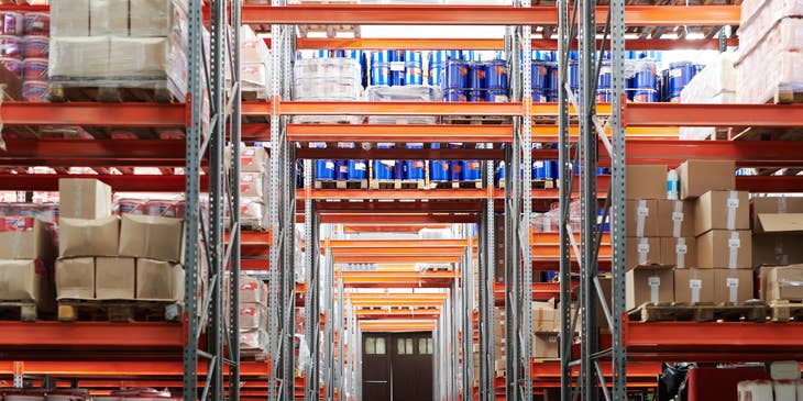 Vista de inventario en un pasillo de almacén, con estanterías y productos.