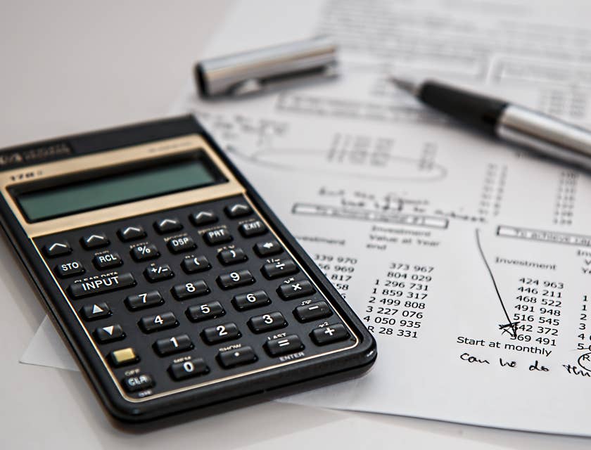 Calculadora, documentos financieros y un bolígrafo en la mesa de un empleado de nóminas.