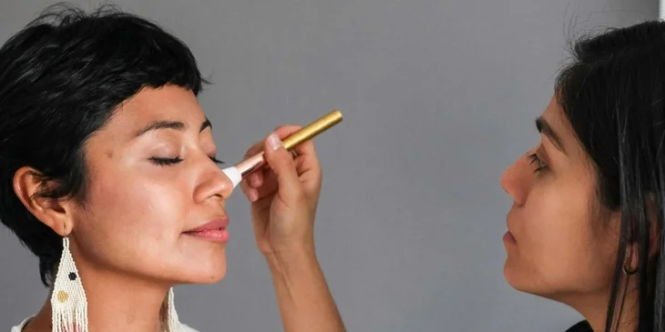 Une maquilleuse qui met du blush sur une cliente.