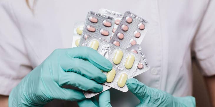La dependienta de una farmacia contratada por una bolsa de trabajo de la industria farmacéutica sosteniendo pastillas con sus manos.