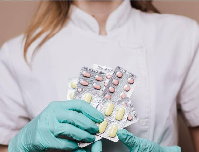 La dependienta de una farmacia contratada por una bolsa de trabajo de la industria farmacéutica sosteniendo pastillas con sus manos.