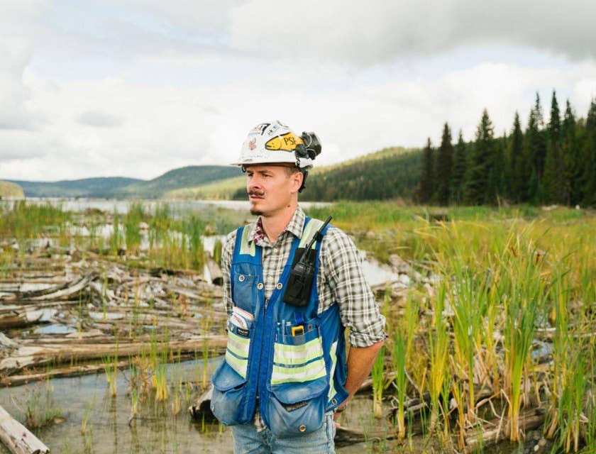 Un ingeniero ambiental con casco y chaleco trabajando en un sitio de ingeniería ambiental.