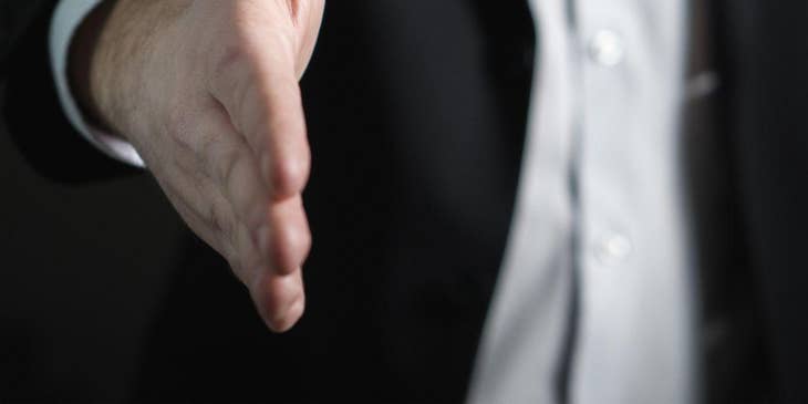 Un hombre haciendo una oferta de trabajo y extendiendo una mano.