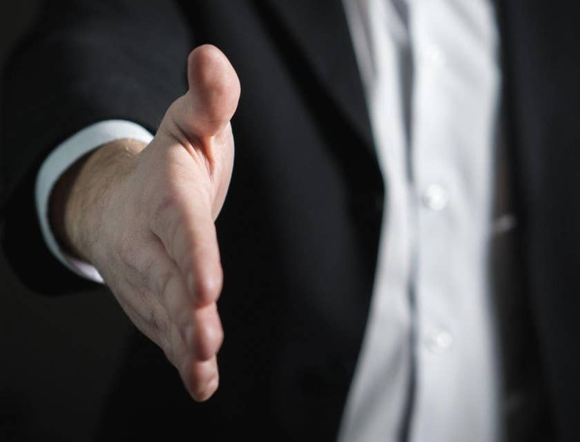 Un hombre haciendo una oferta de trabajo y extendiendo una mano.
