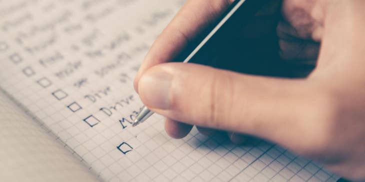 Una mano haciendo una lista de modelo de competencias en un cuaderno.