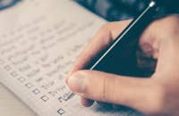 Una mano haciendo una lista de modelo de competencias en un cuaderno.