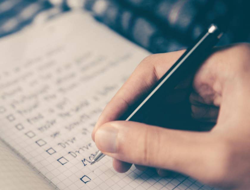Una mano haciendo una lista de modelo de competencias en un cuaderno.