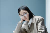 Una empleada sentada aburrida en su escritorio recargando la cabeza en su mano.