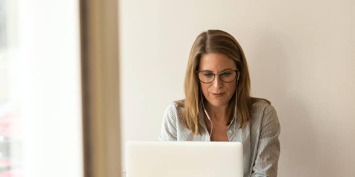 Business Manager checks performance data on a laptop while taking calls using a headphone