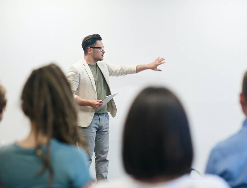 A Campus Recruiter holding a tablet talking in front of a group of students.