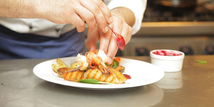 Commis Chef is plating a meal as per head chef's instruction.