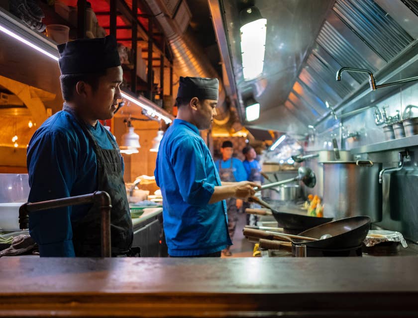 The cook is preparing food  and makes sure it is completed on time.