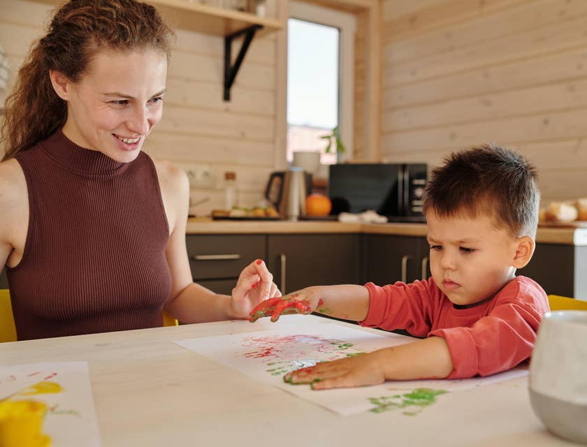 Day Care Director oversees child development as the toddler plays hand painting on a paper