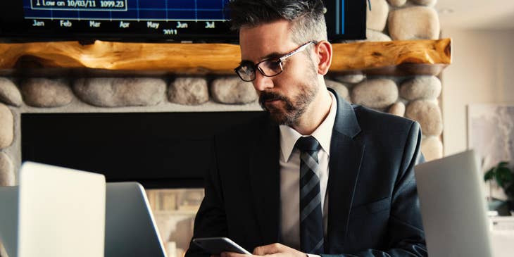 A department head in an office setting on his laptop and phone with co-workers.