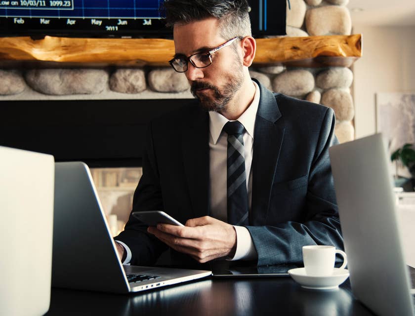A department head in an office setting on his laptop and phone with co-workers.