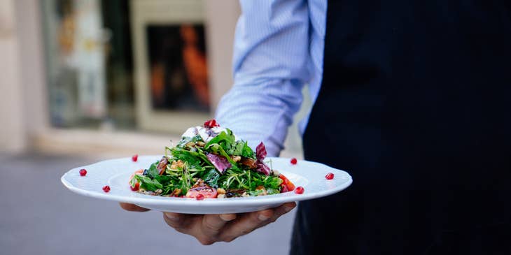 Food Service Worker serving a salad to the customer.