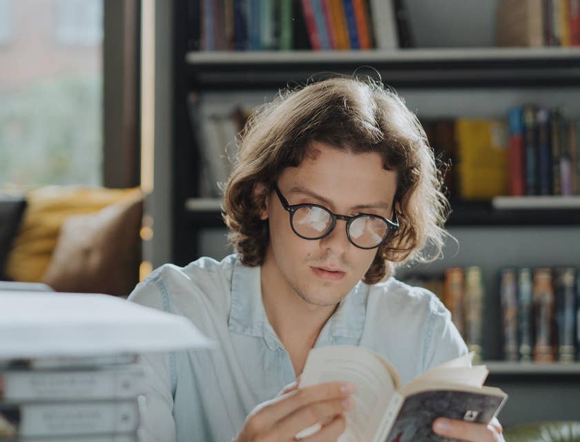 Historian reading several books in a library.