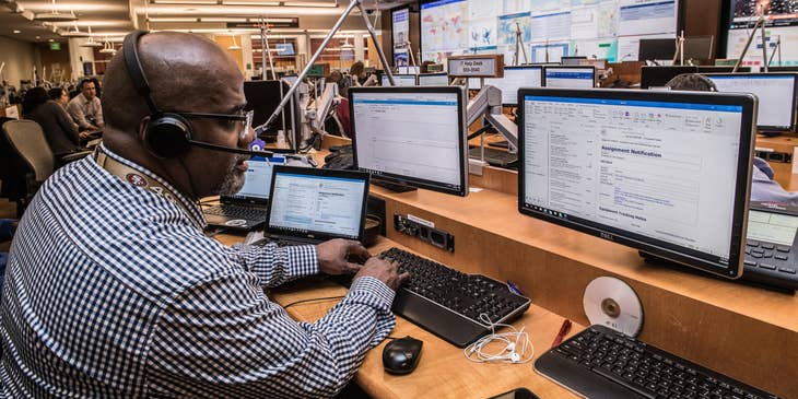 Man with headphones and mic sitting behind an IT help desk