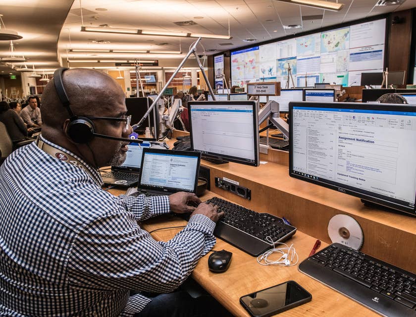 Man with headphones and mic sitting behind an IT help desk