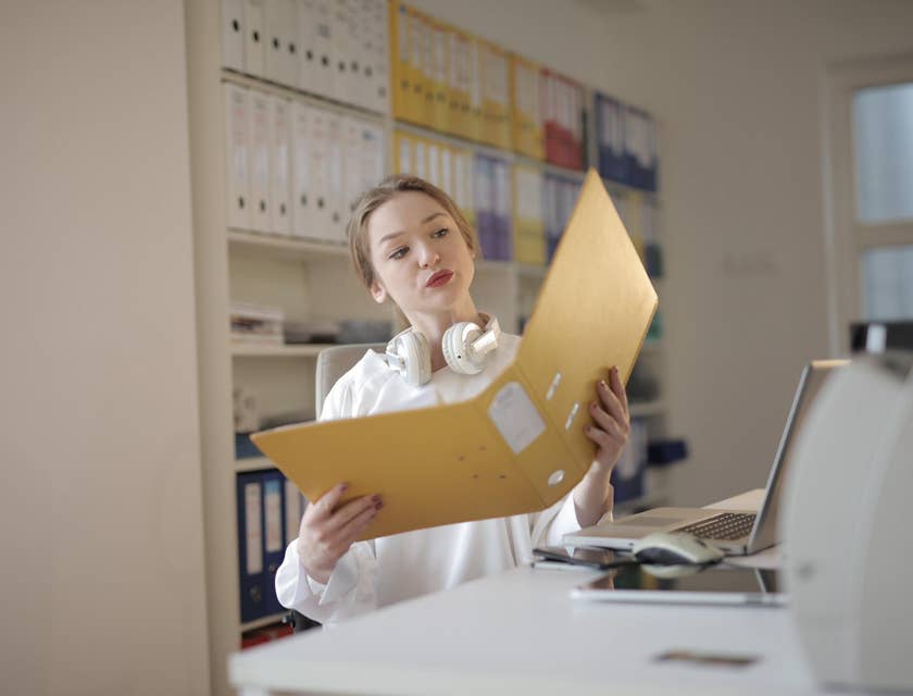 Junior Accountant checks submitted receipts and file invoices in a binder to submit a financial report to the manager