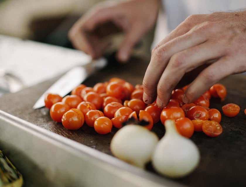 A kitchen helper chopping tomatoes.
