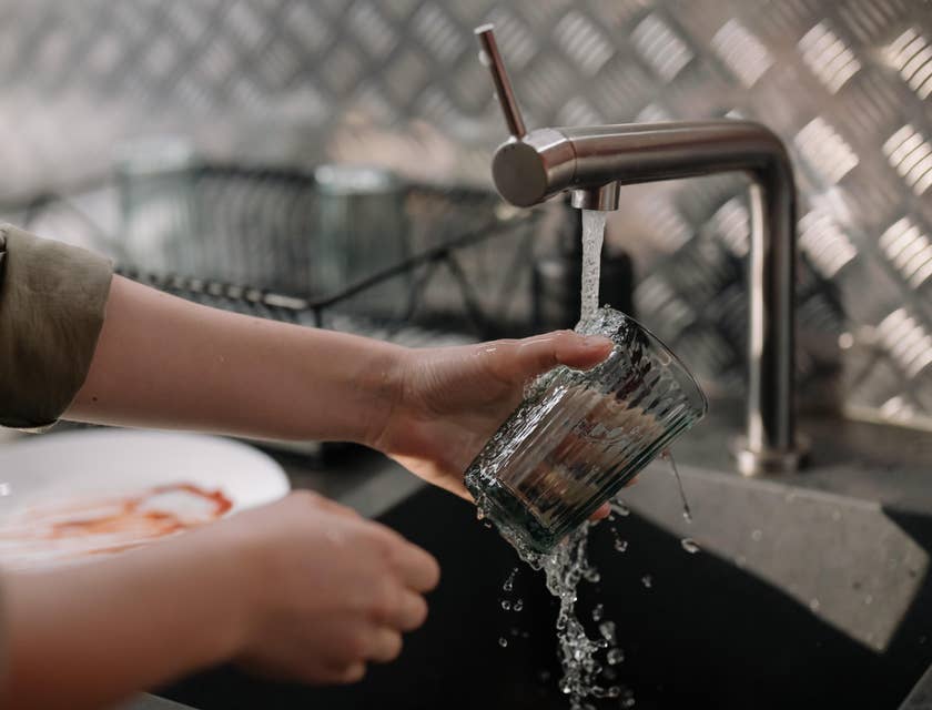 A kitchen porter washing a glass.