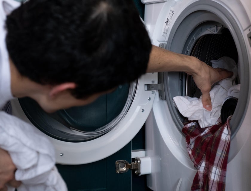 A laundry attendant taking out clothes from the washing machine.