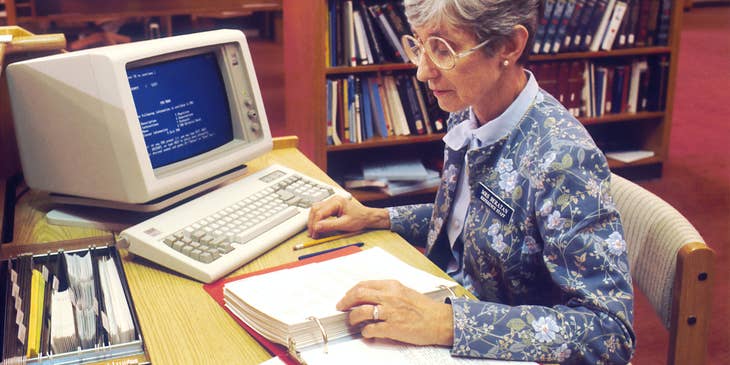 Librarian sitting at her desk reading documents.