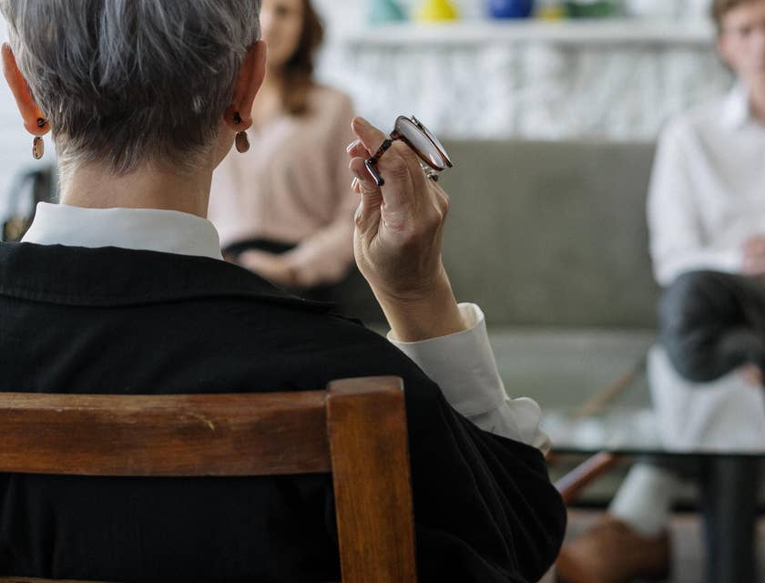 Mediator holding her eyeglasses as she listens to the client's conflict