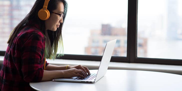 Medical transcriptionist listening on headphones while typing on a laptop
