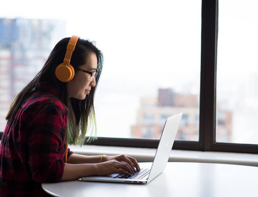 Medical transcriptionist listening on headphones while typing on a laptop