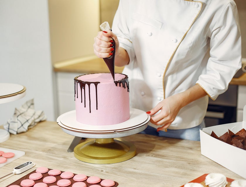 Pastry chef decorating a cake.