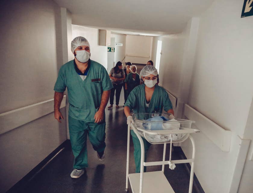 Pediatric nurse carrying a baby in a trolley to the nursery room.