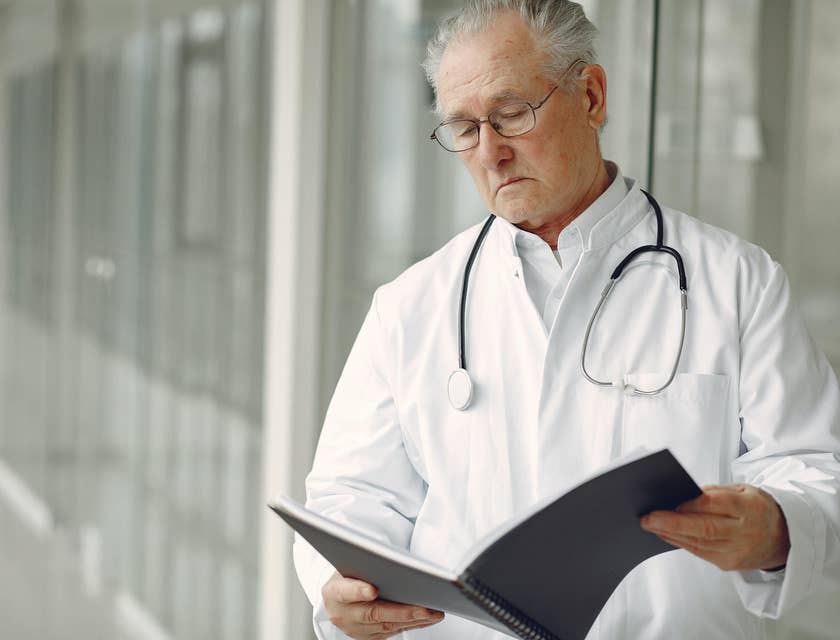 Physician reads clinical history while waiting for the patient outside his office