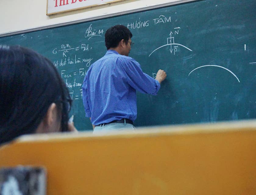 Physics teacher explaining the formula to students while writing on the board