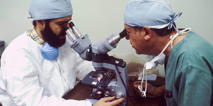 Physiologist is studying a bacteria under the microscope with an assistant