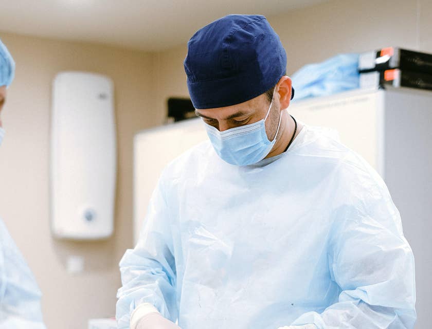 Plastic surgeon cutting a surgical thread as he finishes the operation.