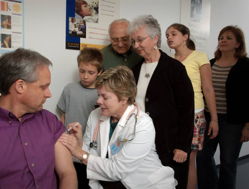 RN case manager injects flu vaccine to the patient while promoting wellness to the patient's family members