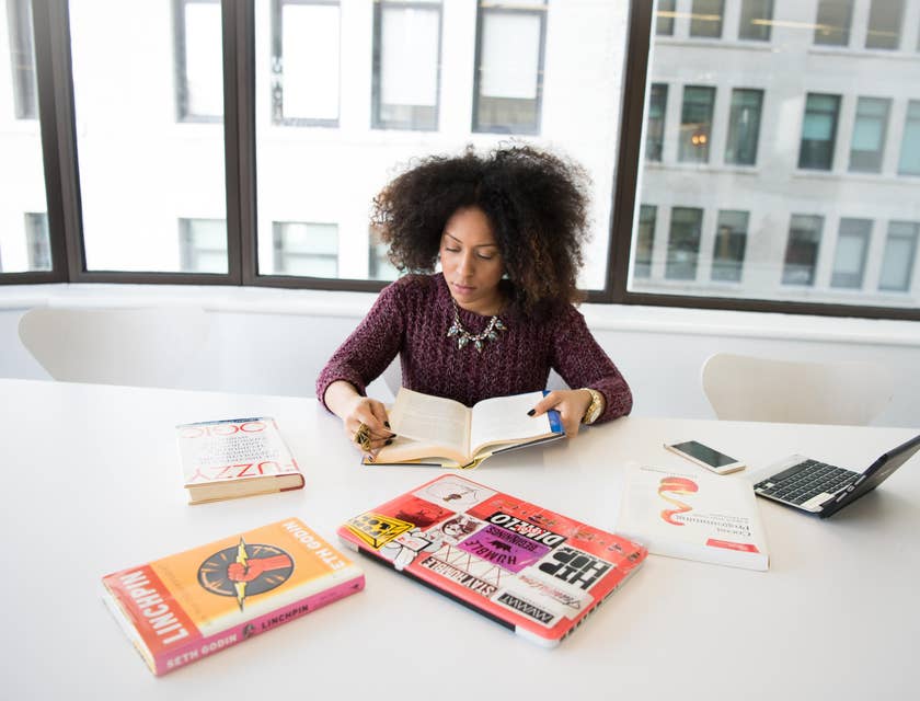 Researcher reading several books to gather information on her research data