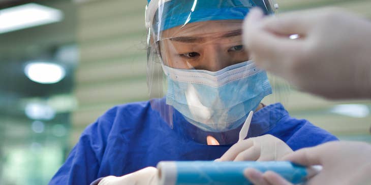 Respiratory therapist clears the patient's mouth airway as they place a breathing tube