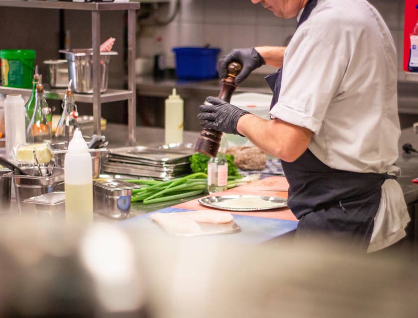 A restaurant cook in a restaurant kitchen setting preparing some ingredients for cooking.