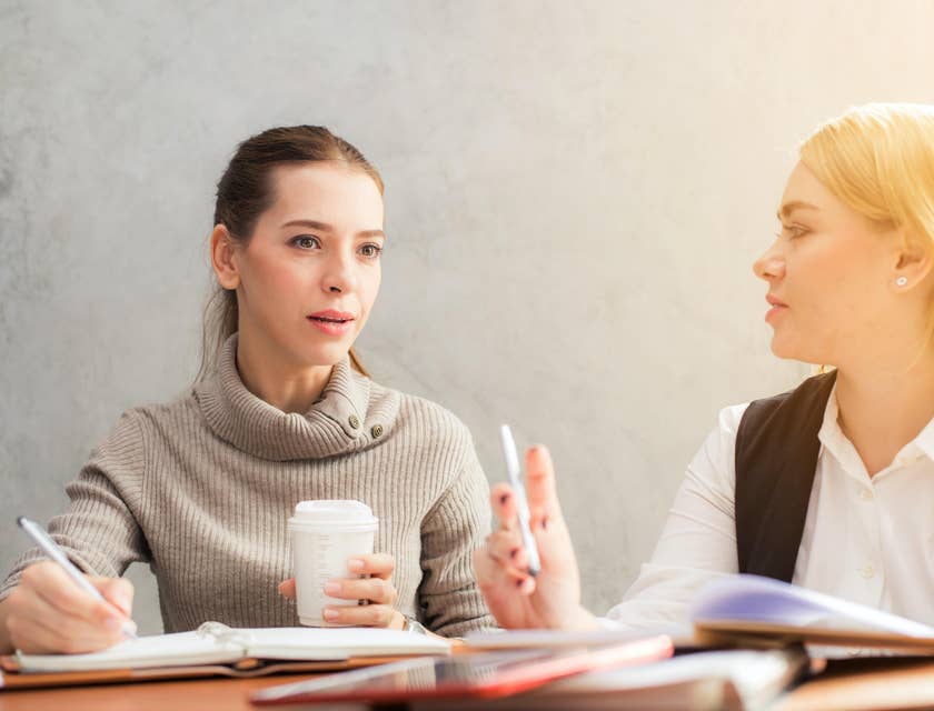 Retention Specialist communicates with sales rep discussing strategies while taking notes and drinking coffee