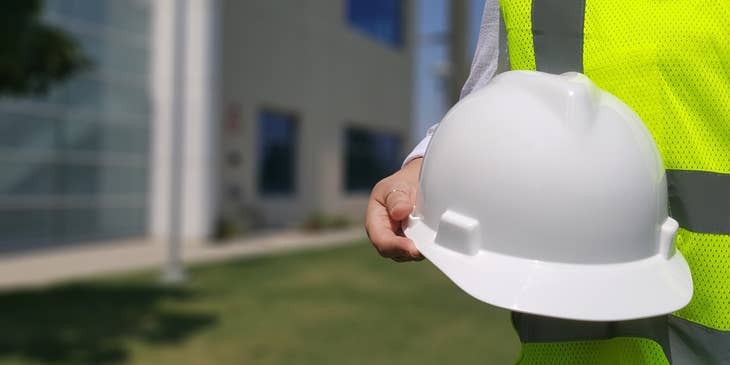 Safety officer holding his safety hat on his way to ensure workers are practicing safety measures.