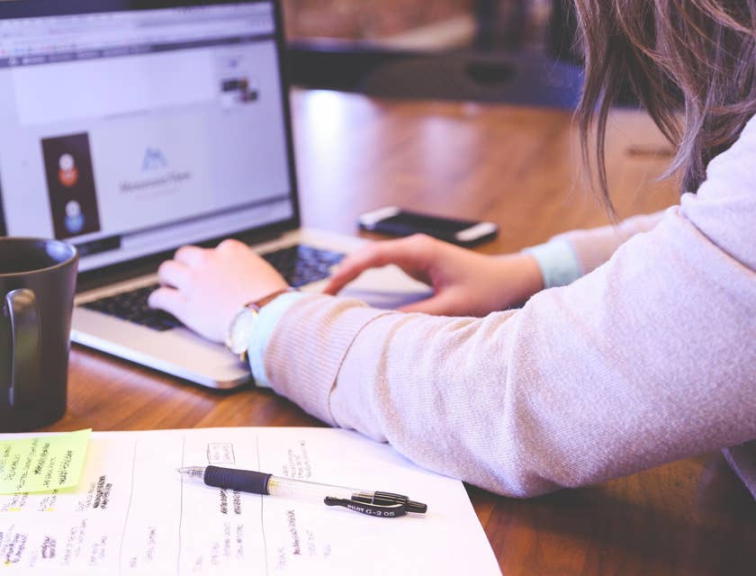 Senior product marketing manager researching marketing to increase market shares using her laptop and notes