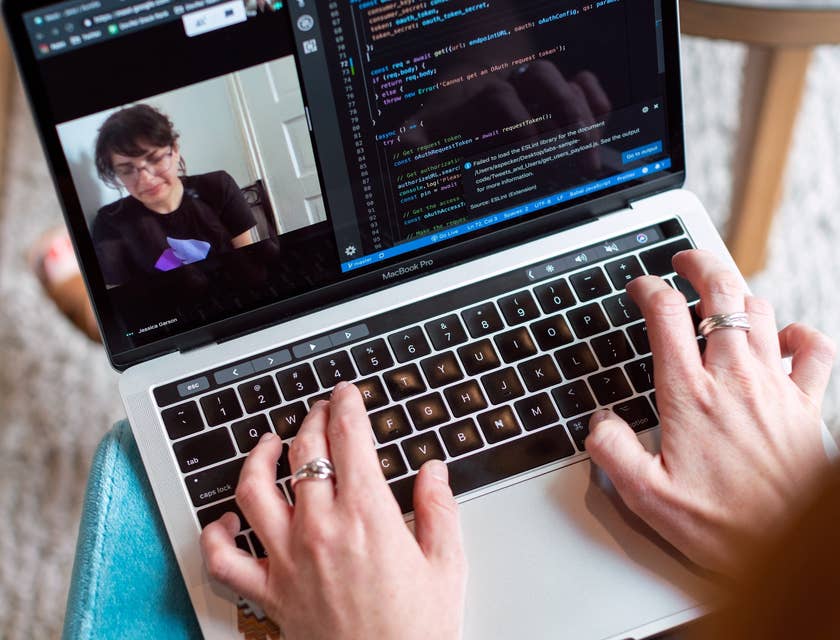 Software Project Manager works on a software program while on a video call with a client to discuss a new application