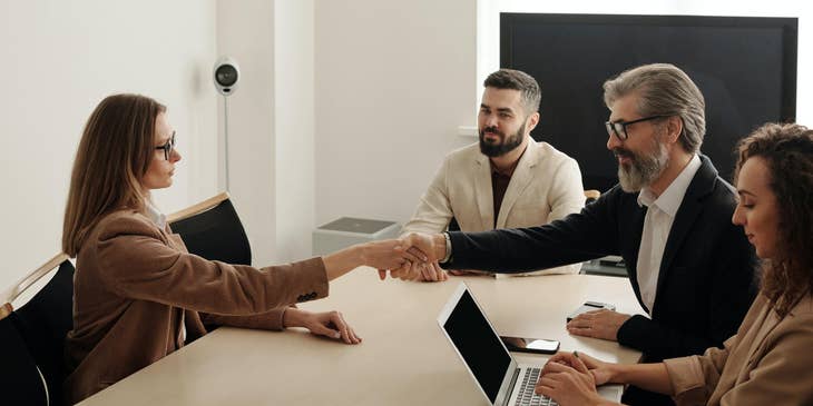 Strategic planner shaking hands with client after agreeing on the short and long term goals of the company.