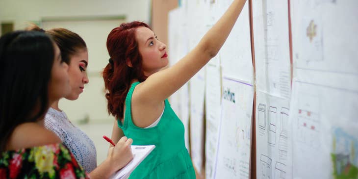 Substitute Paraprofessional checks assigned lesson sections on the board with co-workers