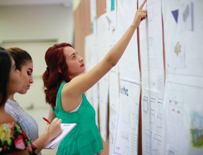 Substitute Paraprofessional checks assigned lesson sections on the board with co-workers